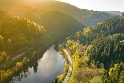 Peaceful valley with flowing river, surrounded by wooded hills at sunset, emptied Schwarzenbach