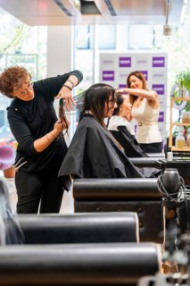 Professional hairstylists providing hair care services to female clients, cutting and styling hair
