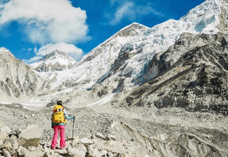 Woman trekker alone stands by EBC viewpoint in Sagarmatha national park with mountains background.