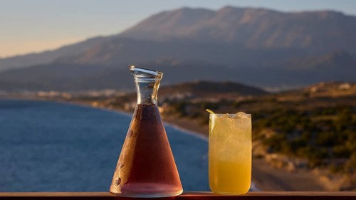 Two drinks on a railing with a view of sea and mountains at sunset, Matala, South Coast, Crete,