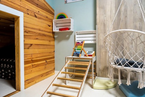 Bright modern children's playroom with wooden climbing frame, abacus, rainbow stackers, playful