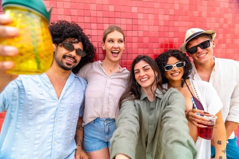 Group of happy young diverse friends smiling and laughing at the camera, capturing a joyful moment