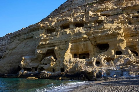 Neolithic caves, former hippie paradise, impressive rock wall with caves on the beach in sunlight,