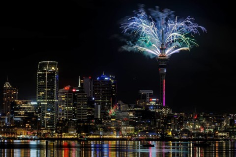 Fireworks exploding beside the Sky Tower at midnight to welcome the new year, Auckland, New Zealand