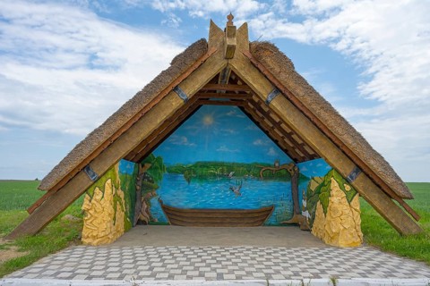 Shelter with thatched roof and paintings of a lakeside landscape, quiet rural area, bus stop,