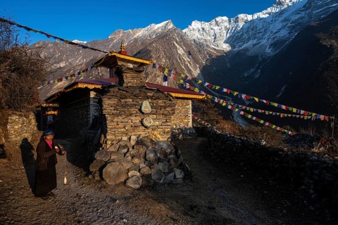 Young woman next to a small Buddhist monastery with manistones in the evening light, Nepalese,