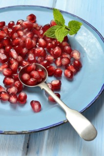 Pomegranate seeds and spoons on plate, Punica granatum