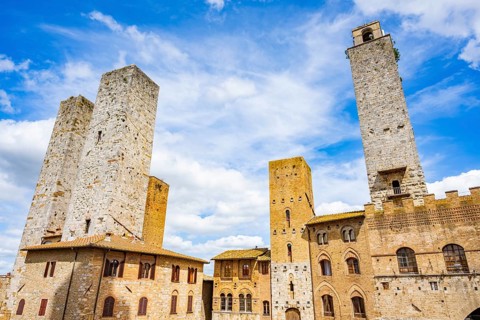 Towers of the old Town with historic buildings from Piazza del Duomo at San Gimignano on a sunny