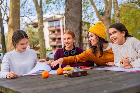 Family consisting of a mother and her three daughters learning and studying together with books and