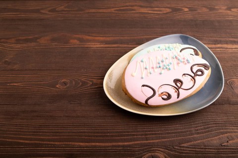 Glazed pink and blue decorated cookies, on brown wooden background, copy space, side view