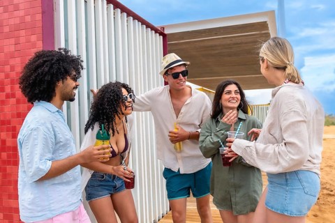 Diverse group of young adult friends laughing and talking together while holding refreshing drinks