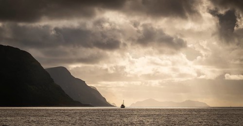 Dramatic lighting and dark clouds over the sea, island, ship, near Ålesund or Alesund, Møre og