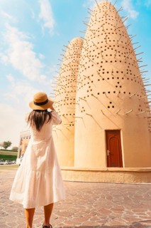 Doha, Qatar - 15th january, 2026: Woman traveler tourist taking picture of Katara pigeon towers in