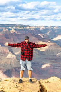 Traveler standing with arms open wide on a viewpoint overlooking the vast expanse of the grand