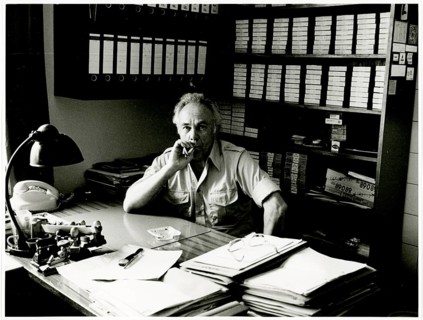 A man sits deep in thought at a desk in a tidy office full of documents and files: Herbert Jacobi