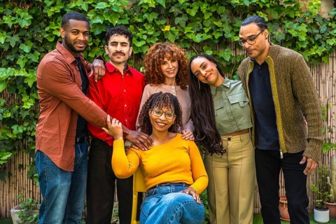 Diverse group of adult friends embracing each other, smiling while posing in a garden setting,