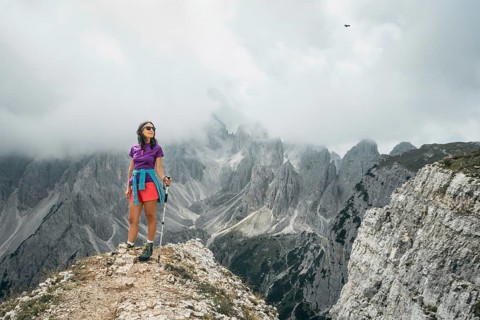 Woman hiker on viewpoint by Dramatic jagged limestone peaks Sesto Dolomites range sharp spires