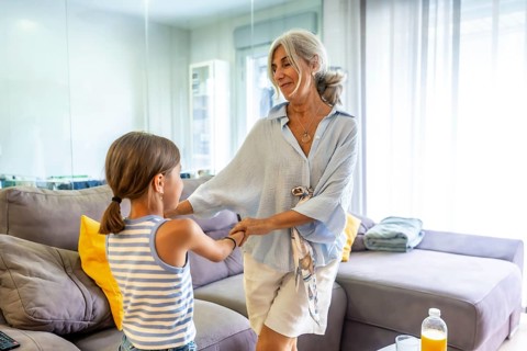 Grandmother and granddaughter smiling and holding hands, sharing a loving moment together in a