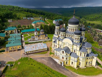 Extensive monastery complex with distinctive yellow buildings and domes under cloudy sky, aerial