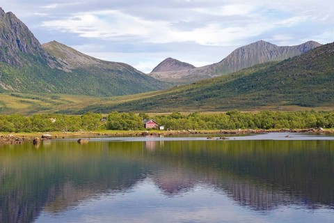 A pink house by the lake with surrounding mountains, Andoeya, Nordland, Vesteralen, Norway