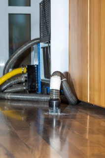 Professional water damage repair Drying equipment and hoses for underbody drying on wooden floor