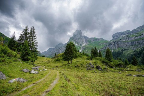 Hiking trail in a valley, rocky peak Spaltenhorn, mountain landscape with dark clouds, Bernese