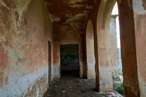 Dilapidated corridor with worn walls and arches in a historic ruined building, Lost Place,