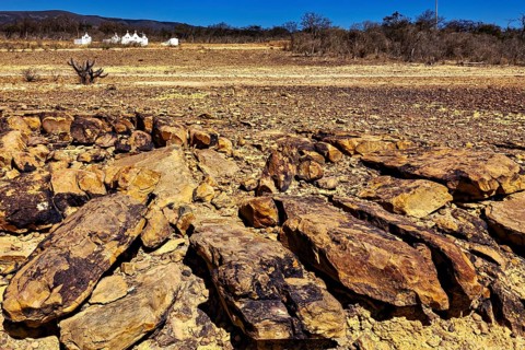 Massive rock formations on dry soil with sparse vegetation under clear skies, the thornshrub