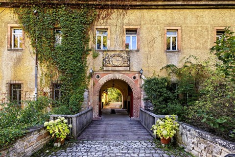 A historic entrance gate with bridge and blooming plants, Tonndorf Castle in the Weimar region in
