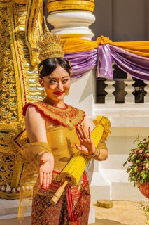 Young Thai woman in traditional dress poses in front of photographers at the Wat Phra Singh