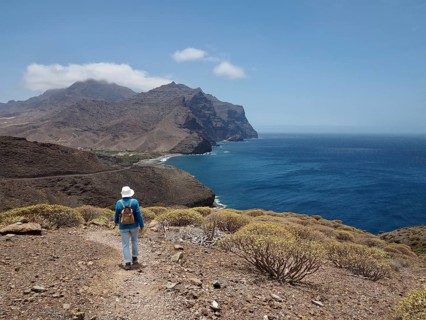 Female hiker on a rocky path with views of the coast and the sea, La Aldea de San Nicolas, Gran
