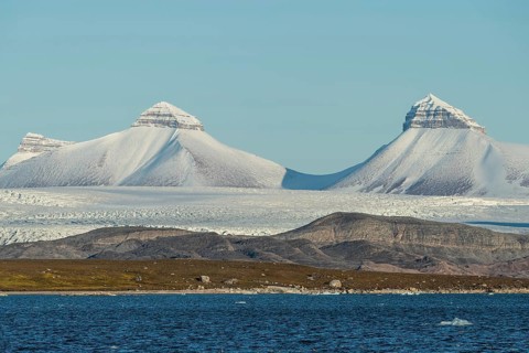 A fjord with ice floes and two of the three mountains: Tee Kroner (Three Crowns), Kronebreen or