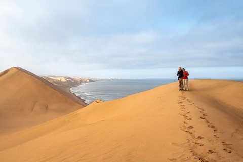 Couple standing on a sand dune, sand dunes and sea in morning light, Atlantic coast and sandy