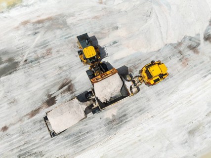 Excavator and lorry at a harvesting pan of the Walvis Bay Salt works. Aerial view. Drone shot.