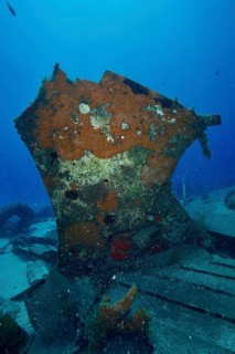 A vertical, rusty piece of wreck surrounded by sand and marine life, meteor wreck dive site,
