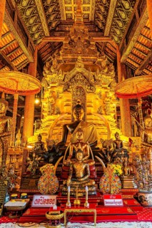 Sumptuous interior with richly decorated wooden ornaments, gilded Buddha statues, Buddhist temple