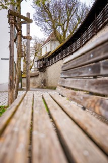 Empty wooden bench in front of a long, arched stone structure in a rural area, Isny, Allgäu,