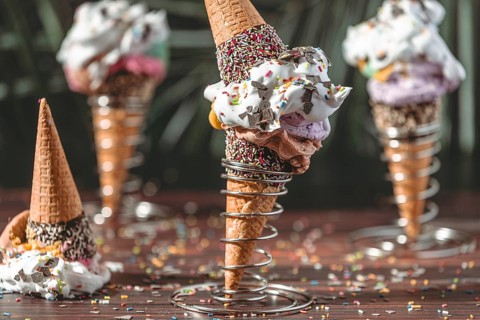 Ice cream cones decorated with ice cream, lots of cream and colorful sprinkles