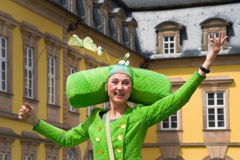 An artistic performance by a fairytale-like costumed stilt walker, visually impressive walking act,