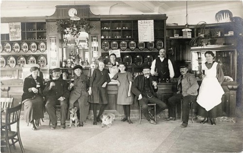 Guest room, pub, restaurant, group sitting happily at a bar with beer barrels in the background,