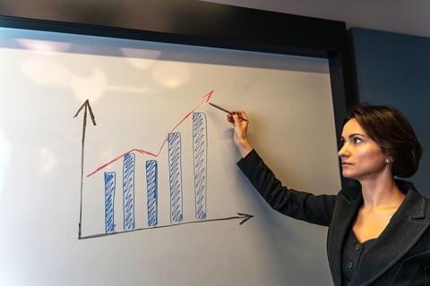 Serious businesswoman analyzing growth chart with pointer during corporate presentation