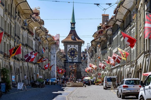 Kramgasse with historic houses decorated with cantonal flags and Swiss national flags, back clock