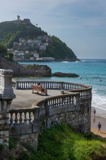 Woman sitting on a bench on the promenade at Bicentennial Balcony, La Concha beach, San Sebastián,