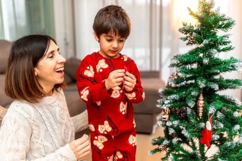 Happy mother and young son spending quality time together, decorating a festive christmas tree in