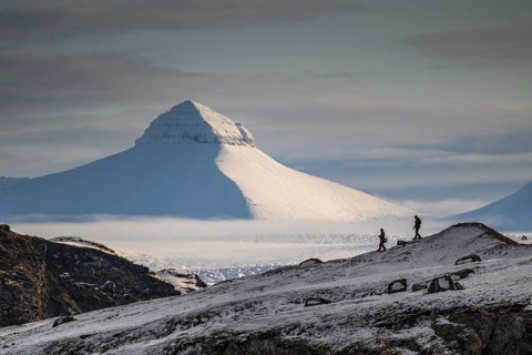 Two people, including a photographer with a stand in front of one of the three mountains Tee