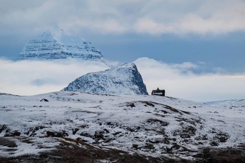 Large rock behind clouds cover one of the three mountains Tee Kroner, Kongsfjord or Kongsfjorden,