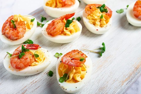 Boiled eggs stuffed with yolk and seasoned with mayonnaise, stuffed eggs with shrimp, on a white