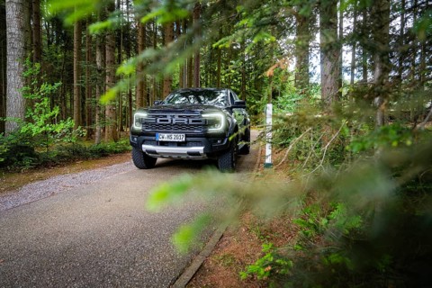 Car driving on a summer forest road surrounded by green vegetation, district service with Björn