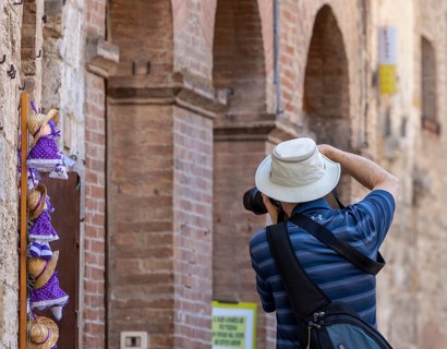 Tourists around the market square with old fountain and other sights in San Gimignano, Tuscany,