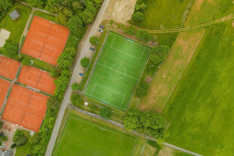 Aerial view showing soccer field and several tennis courts surrounded by nature, Aidlingen sports